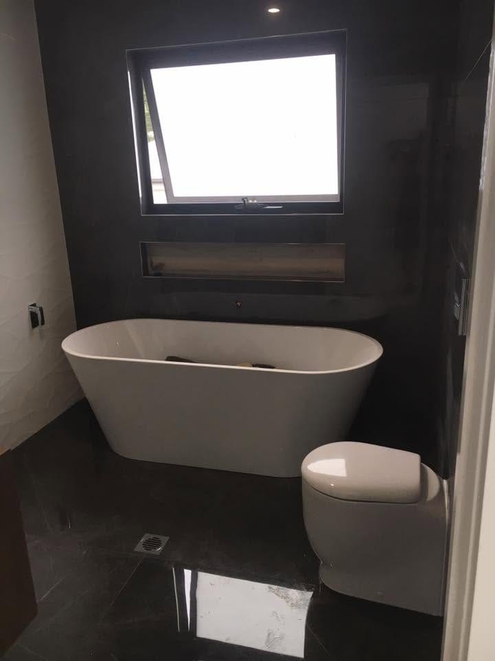 Freestanding bath on dark polished floor — tiling by Torrisi Tiling, Brisbane