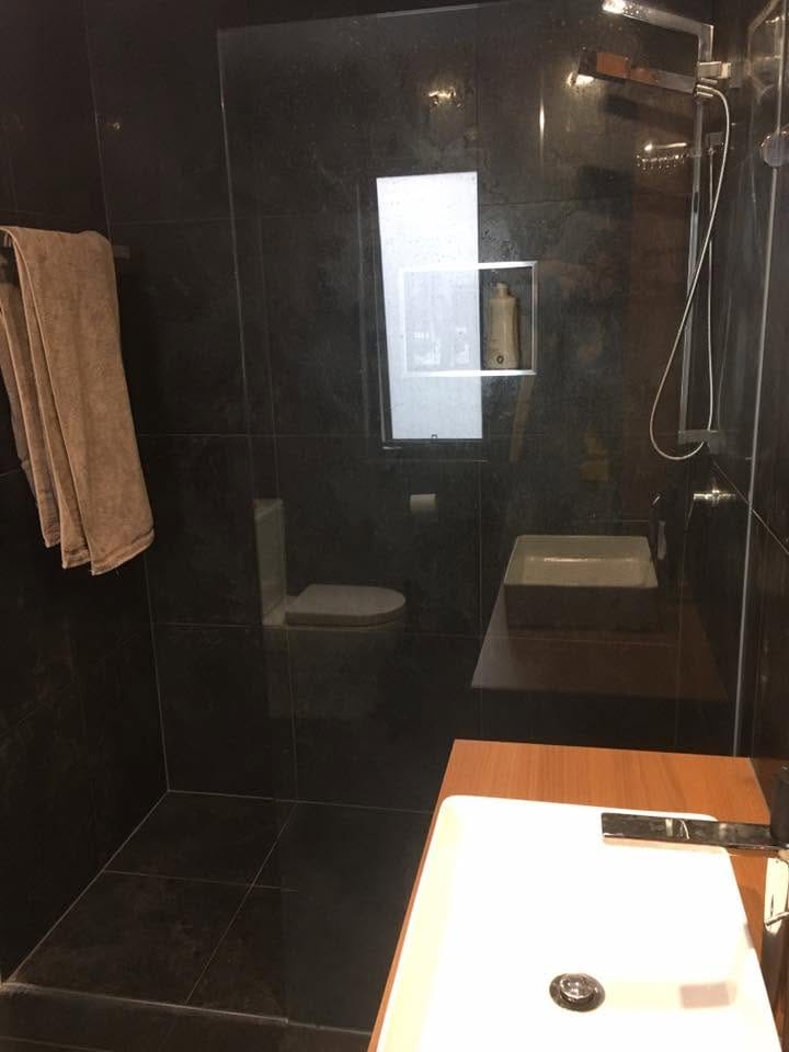 Dark shower with timber accents — tiling by Torrisi Tiling, Brisbane